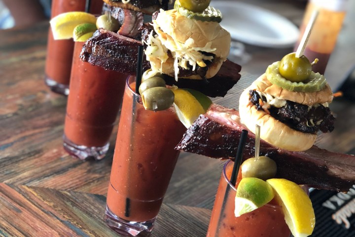 Five Bloody Marys with sliders, ribs, olives, and pickles skewered on top.