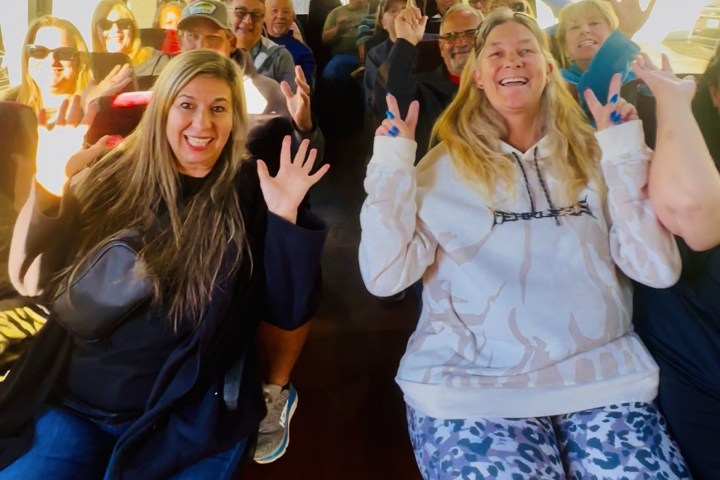 Group of people smiling and waving inside a bus.
