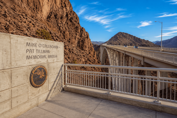 Bridge over canyon with sign 'Mike O'Callaghan-Pat Tillman Memorial Bridge' and blue sky.