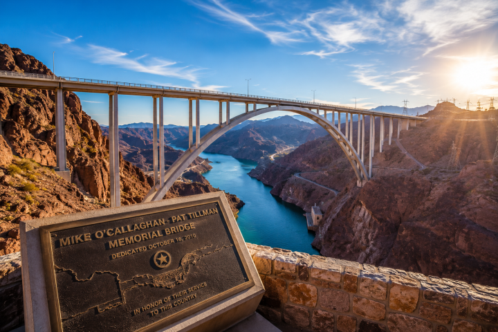 Bridge over canyon and river with a memorial plaque in foreground at sunrise.